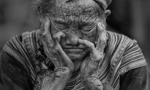 Schlaf, alte sitzende Frau schläft mit Händen vorm Gesicht